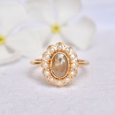 "A cozy fresh water pearl halo around a 1.27 carat chocolate brown rough diamond, bezel set in solid 14k gold - this ring is a hot chocolate on a cold day! A perfect alternative bridal ring, this unique ring also makes for a stunning long distance winter holiday gift! * Gold : 14k Solid Yellow Gold * Gold Wt. : ~3.5gms * Gemstone 1 (Centre) : Natural Diamond * Diamond Color : Light Muddy Brown * Diamond Weight : 0.76 Ct * Gemstone 2 (Halo) : Fresh Water Pearls * Weight : 0.66 Ct * Authenticity C Luxury Pearl Ring With Rose Cut Diamonds For Anniversary, 14k Gold Pearl Ring With Rose Cut Diamonds, Gold Diamond Halo Moonstone Ring, Gold Moonstone Ring With Diamond Halo, Heirloom Moonstone Ring With Rose Cut Diamonds For Anniversary, Heirloom Oval Pearl Ring With Rose Cut Diamonds, Gold Oval Pearl Ring With Center Stone, Fine Jewelry Gold Moonstone Ring With Halo Setting, Heirloom Pearl Ring With Rose Cut Diamonds For Anniversary