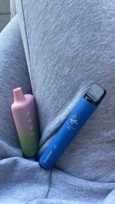 a pink and blue bottle sitting on the back of a couch next to a cell phone