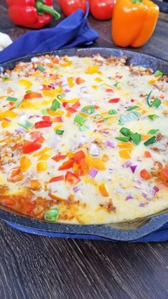 a pizza sitting on top of a blue pan covered in cheese and toppings next to peppers