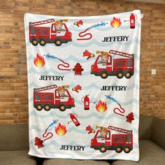 a firetruck blanket is hanging up on a couch in front of a brick wall