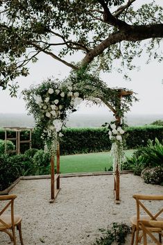 an outdoor ceremony setup with white flowers and greenery