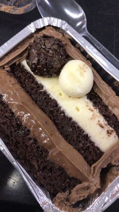 a piece of chocolate cake in a plastic container with ice cream and two scoops