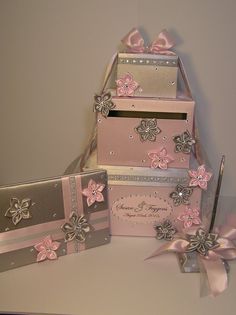 pink and silver boxes are stacked on top of each other, with ribbons around them