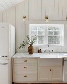 a kitchen with white cabinets and marble counter tops in an attic style home that has wood flooring