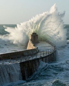 a large wave crashes into the sea wall