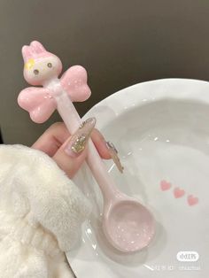 a person holding a spoon in front of a white plate with a hello kitty design on it