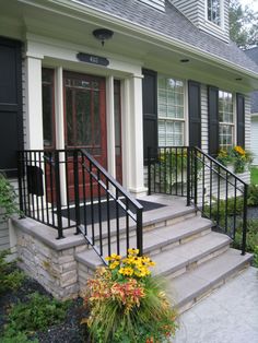 a front porch with steps leading up to the door and flowers growing on the side