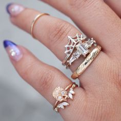 a woman's hand with three different rings on her fingers and one has a spider web ring