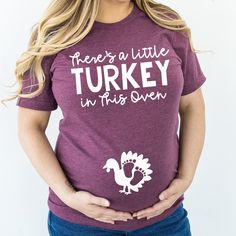 a woman wearing a t - shirt that says, there's a little turkey in this oven