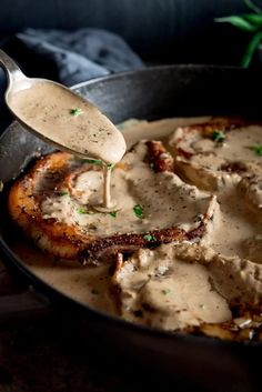 a skillet filled with meat and gravy on top of a wooden table