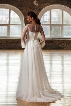 a woman in a white wedding dress standing on a wooden floor and looking off into the distance