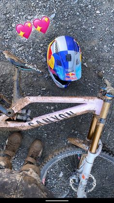 a helmet and some dirt on top of a bike with hearts attached to the front wheel