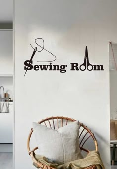 the sewing room wall decal is shown in black on a white wall behind a wicker chair