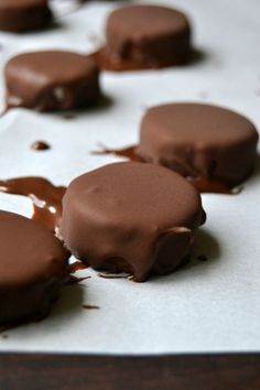 chocolate covered desserts sitting on top of a white paper lined baking sheet with melted chocolate