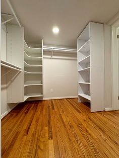 an empty room with white shelves and wooden floors