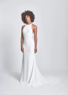 a woman in a white dress posing for the camera with an afro hairdow