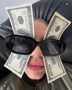 a woman with sunglasses and money sticking out of her face on top of a black leather chair