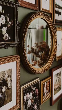 there are many framed pictures on the wall and one has a vase with flowers in it