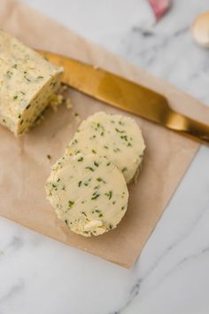 two pieces of bread sitting on top of a piece of paper next to a knife