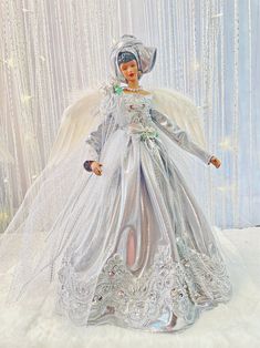 a doll is dressed in silver and white