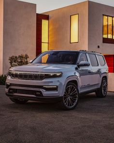 a white jeep parked in front of a house at night with the lights on and windows lit up