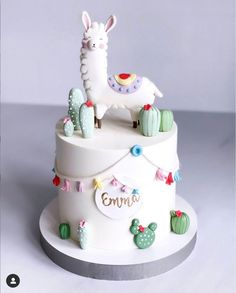 a white cake with a llama and cactus decorations on it's top tier