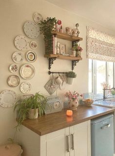 a kitchen with lots of plates on the wall and shelves above the sink, next to a dishwasher