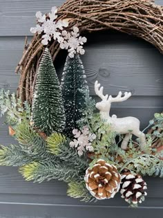 a wreath with pine cones, evergreens and snowflakes is displayed on a door