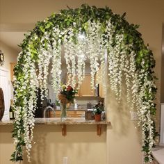 a kitchen area with white flowers and greenery hanging from the ceiling