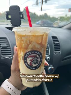 a person holding up a drink in their hand with the words snickkerdoodle drive w / pumpkin drizzle