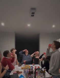 a group of people standing around a kitchen counter drinking from wine glasses and looking up at the ceiling