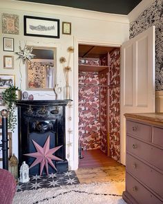 a living room with a fireplace, dresser and pictures on the wall in it's corner