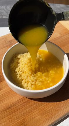 a bowl filled with rice and sauce being poured into it