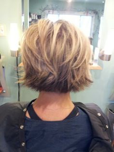 the back of a woman's head with short blonde hair in front of a mirror