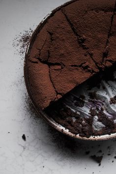 a piece of chocolate cake in a bowl with dirt on the floor next to it