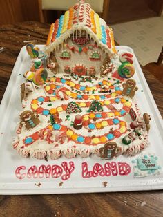 a decorated gingerbread house sitting on top of a white tray with the words candy land written in large letters