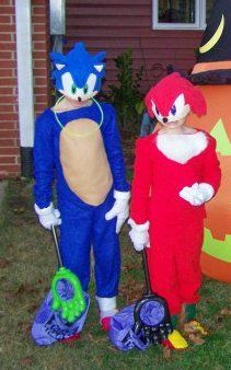 two people in costumes standing next to each other near a large pumpkin and cat costume