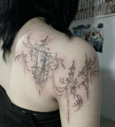 the back of a woman's shoulder with an intricate tattoo design on her upper arm