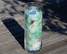 a glass filled with lots of different colored confetti on top of a wooden table