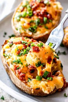 a fork is lifting some food out of a baked bread dish on a white plate