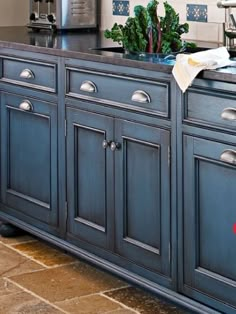 a kitchen with blue cabinetry and stainless steel appliances on the counter top, along with an island in the middle