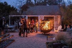 a group of people standing around a fire pit in the middle of a yard at night