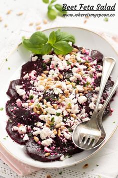 beet feta salad on a white plate with a fork and green leafy garnish