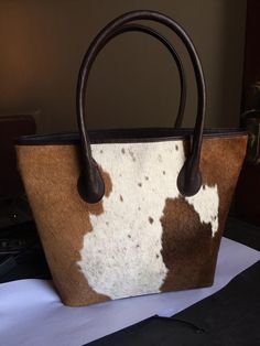 All Our Cowhide Tote Bags Are Free Shipping All Over The World     Size: 37(L) x 39(H) x 10(W) cm  Size:16"(L) x 14"(H) x 5"(W) inches  Custom Made To Order Two Sided Cowhide Tote Purse.  The Cowhide Ladies Bag in brown and white  is the perfect example of our dedicative Craftsmanship with purity of handpicked cowhide. This real cowhide tote bag is designed to keep all your essentials along either getting on board or just heading for a day out with friends. This Cow Hide Duffel is a ready to go Rectangular Cow Print Travel Bag, Cow Print Leather Bag For Daily Use, Rectangular Calf Hair Bag With Leather Handles, Brown Calf Hair Tote Shoulder Bag, Brown Calf Hair Bag For Daily Use, Rectangular Calf Hair Bag For Shopping, Calf Hair Rectangular Shopping Bag, Leather Cow Print Bag For Everyday Use, Calf Hair Tote Shoulder Bag With Leather Handles