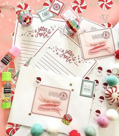 some candy canes and christmas themed items on a pink tablecloth with white envelopes