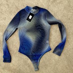 a blue and white bodysuit laying on top of a tan surface with a tag attached to it