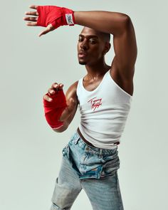 a man in white tank top and blue jeans with red boxing gloves on his arm