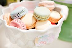 a white bowl filled with different colored macaroons