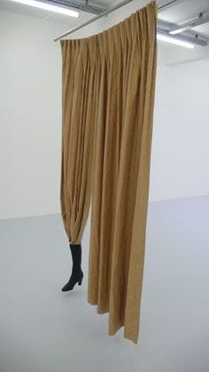 a pair of black boots is standing in front of a curtain that hangs from the ceiling