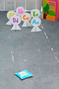 three signs with letters on them sitting in front of a fence and a blue bag